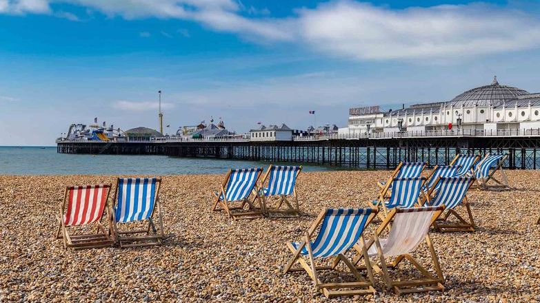 Deckchairs on Brighton beach overlooking pier