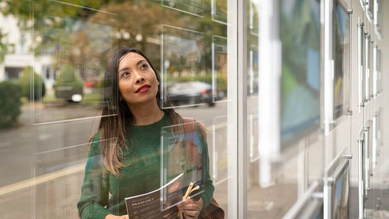 Woman in green jumper looking in an estate agent's window