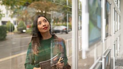 Woman in green jumper looking in an estate agent's window