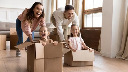 Parents pushing children in cardboard boxes 