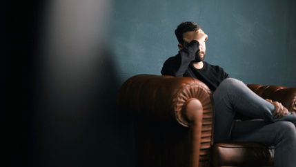 Man holding head on sofa