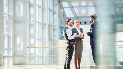 Group of business people talking in office foyer