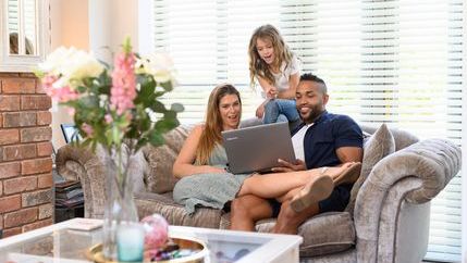 Family looking at laptop on sofa