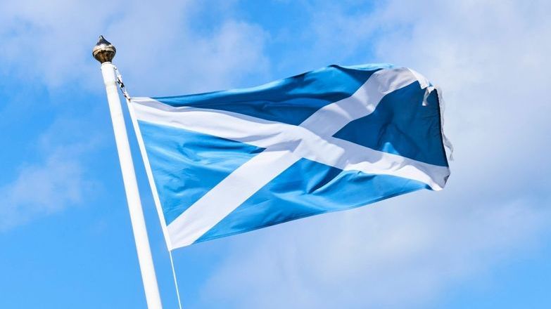 Scottish flag blowing in the wind against a blue sky