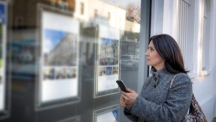 Dark haired lady looking in properties in branch window