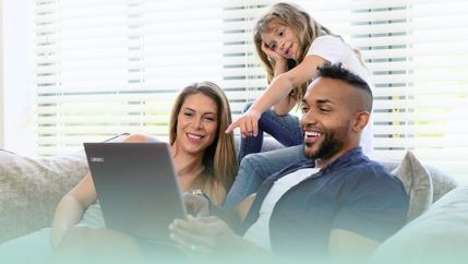 Family looking at a laptop on sofa