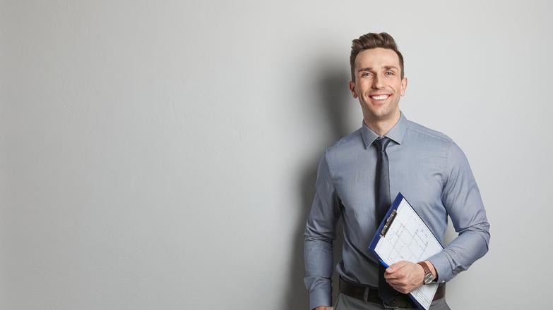 Professional man in grey shirt and tie holding a clipboard 