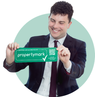 Smiling man in a suit holding a green Propertymark certification sticker