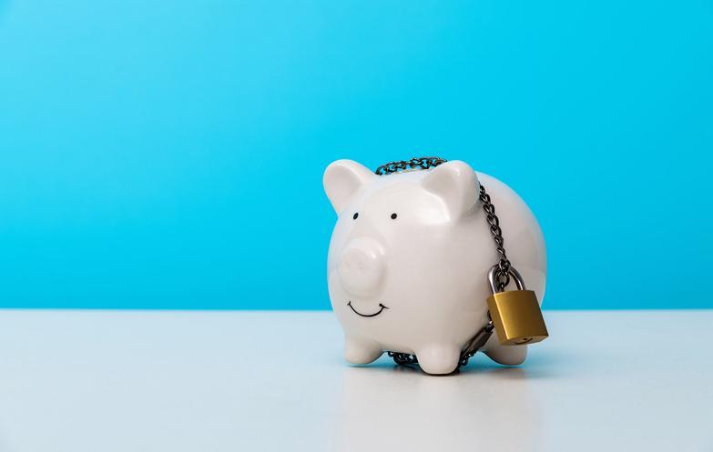 Smiling white piggy bank secured by padlock and chain against a blue background