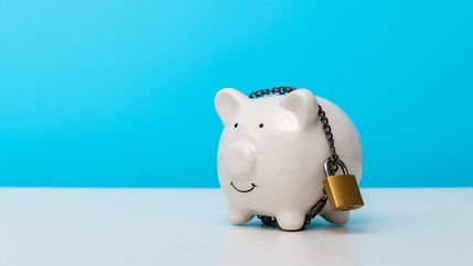Smiling white piggy bank secured by padlock and chain against a blue background