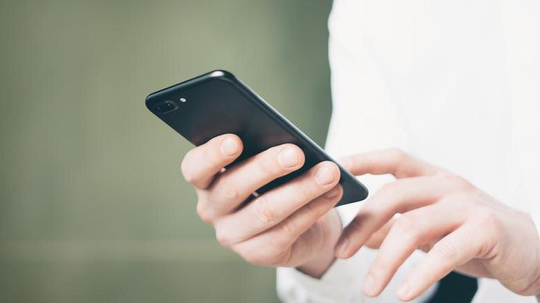 Man in a white shirt holding a phone
