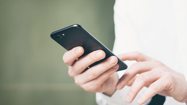 Man in a white shirt holding a phone