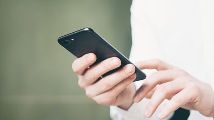 Man in a white shirt holding a phone