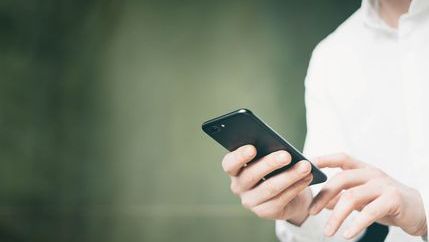 Man in a white shirt holding a phone