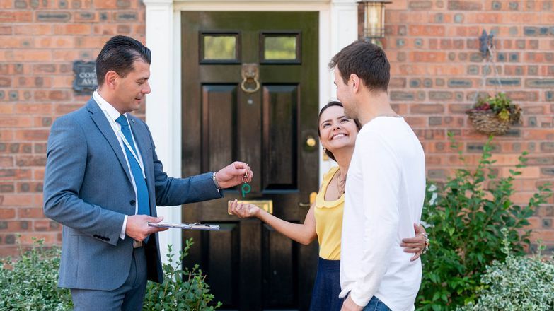 Male agent handing key to young couple