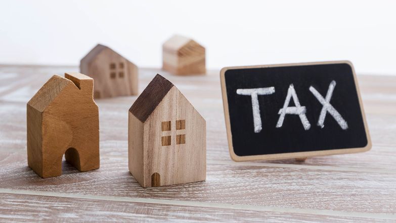 Tax written on chalkboard next to some model houses