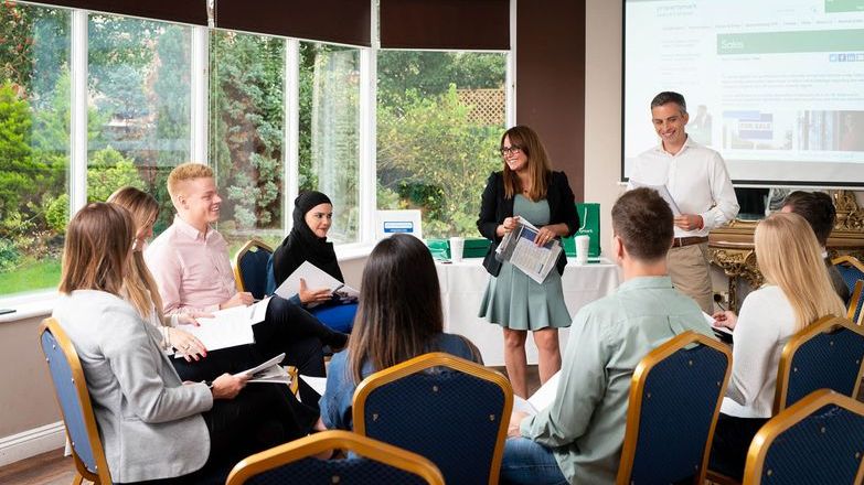 Group of people in a learning environment listening to tutor