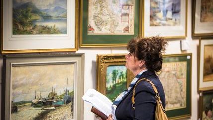 Lady looking at art in auctioneers hall